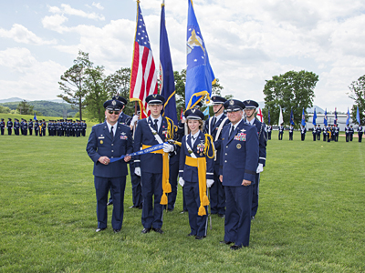 Senior Aerospace Instructor Lt Col R.G. McManus '80, P'08, '13, Cadet Corps Commander Ben Gillis '14, Cadet Vice Corps Commander Grace Alexander '14, and R-MA President Maj Gen Maury Forsyth place the Air Force JROTC Distinguished Unit with Merit ribbon on the R-MA flag. 