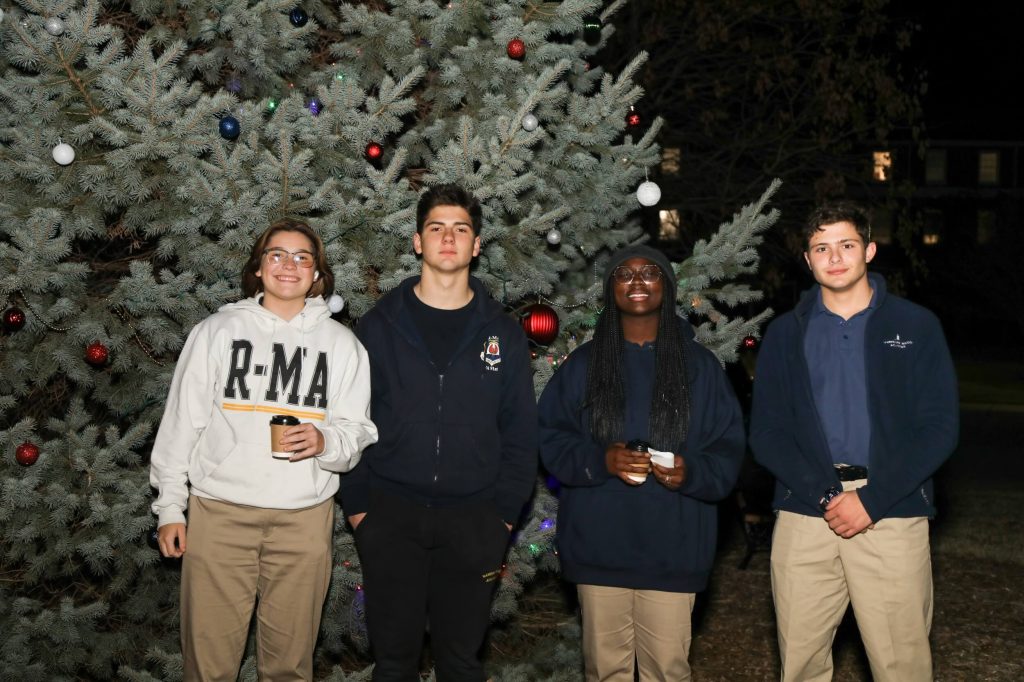 Four R-MA students standing in front of a Christmas tree.