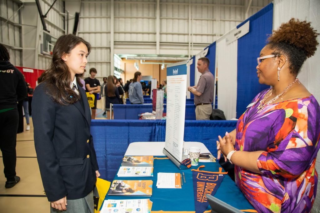 A female R-MA student interacting with a university representative at a university fair