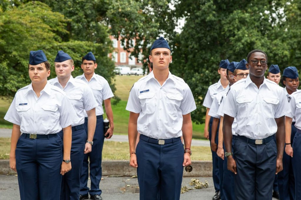 A group of college prep school students performing drills in uniform.