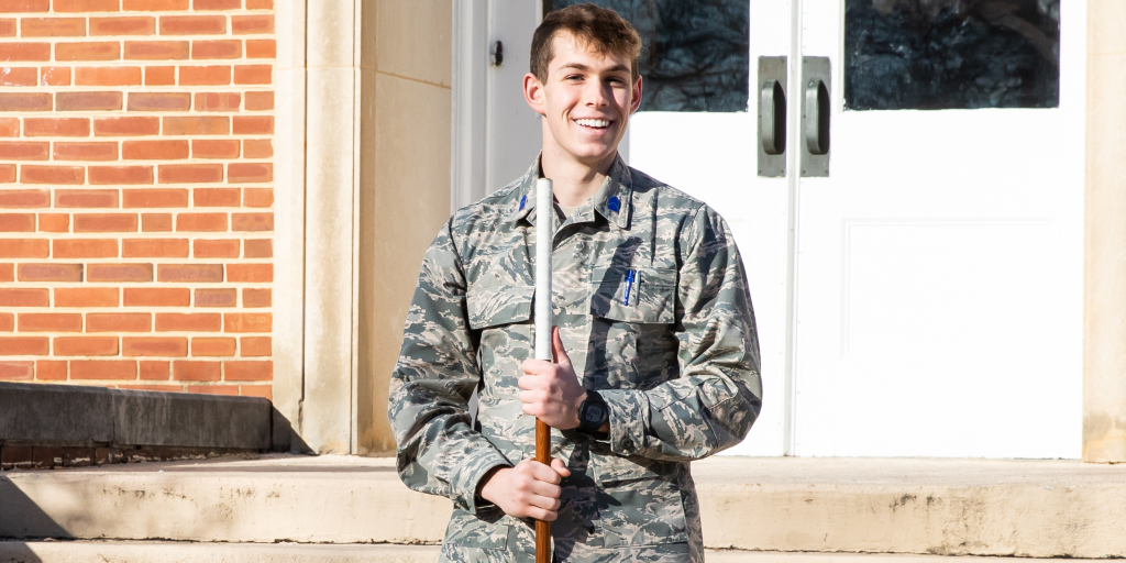 A student in cadet leadership stands outside in uniform