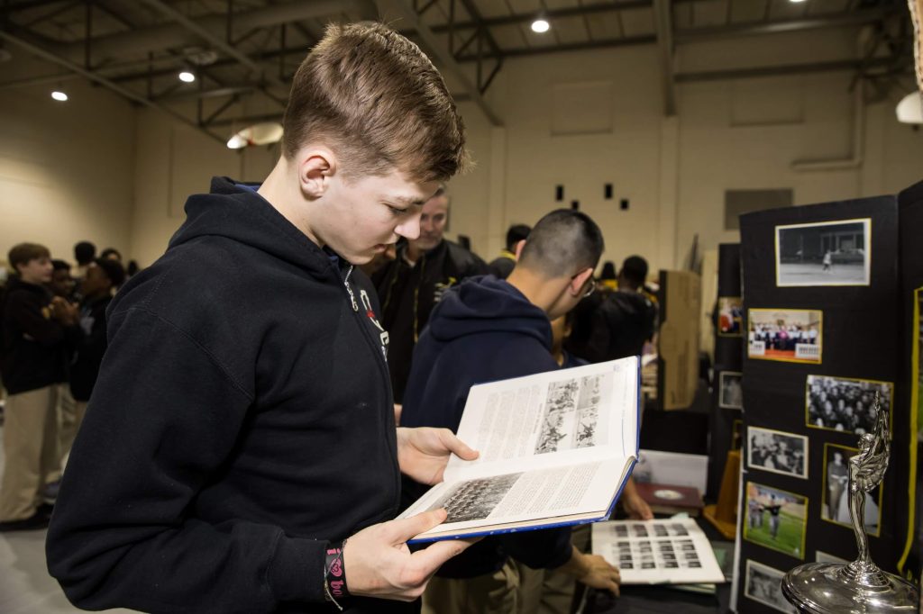 A male student reading a college book at a university fair at our private school