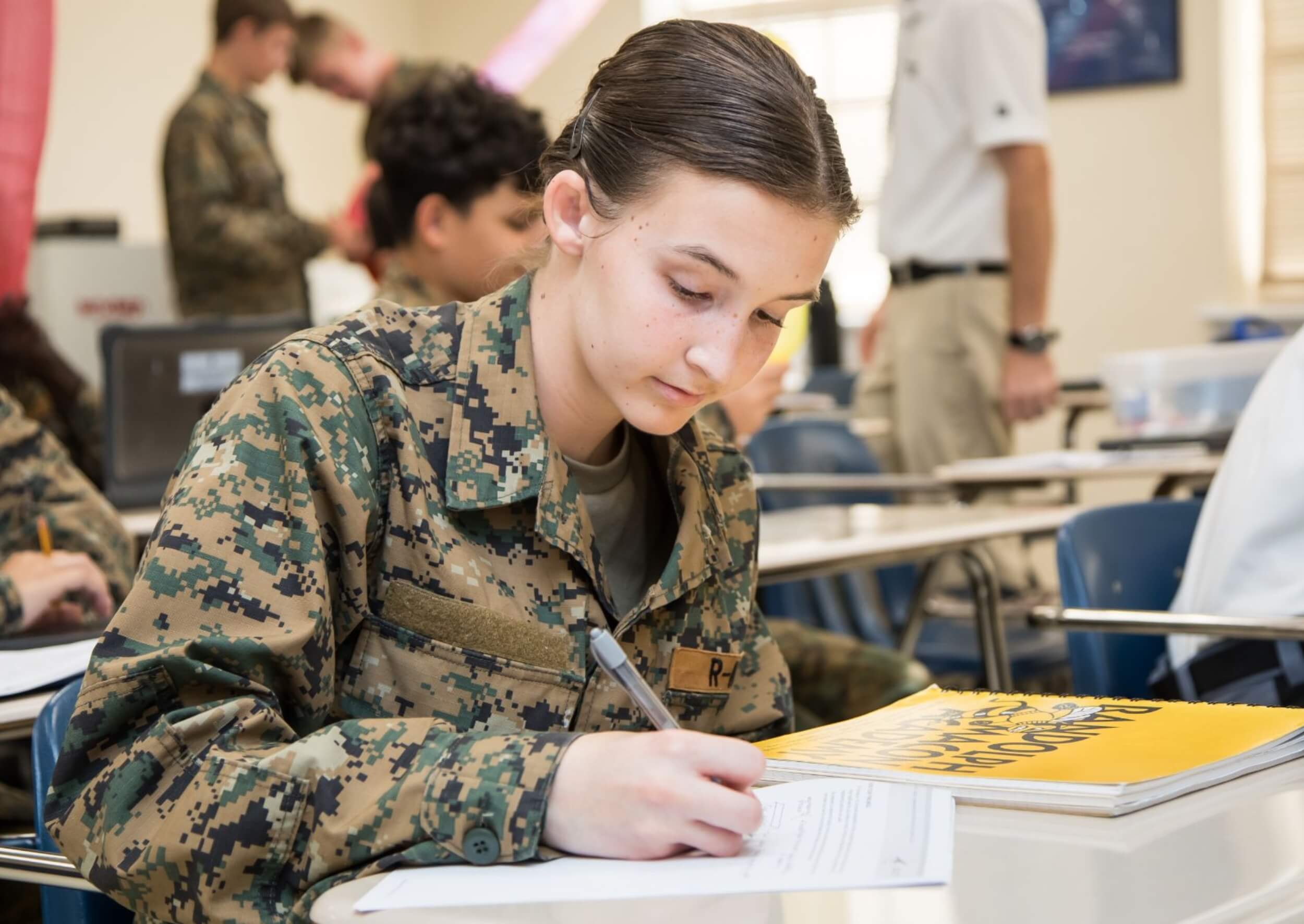 An R-MA student in uniform completing coursework in a classroom