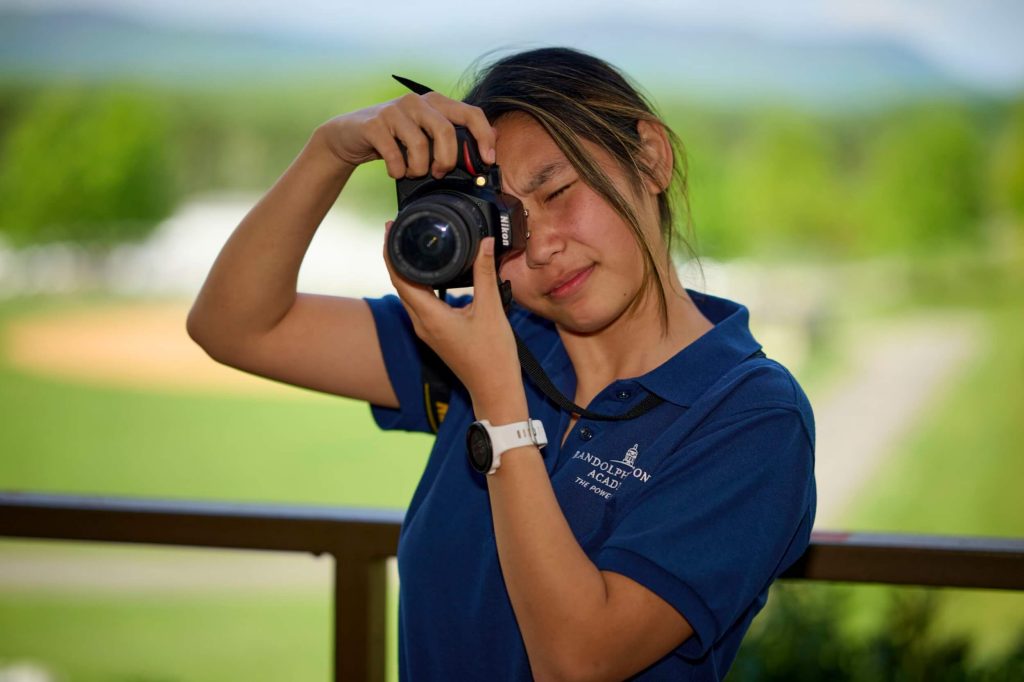 An R-MA student practicing photography outdoors on campus.