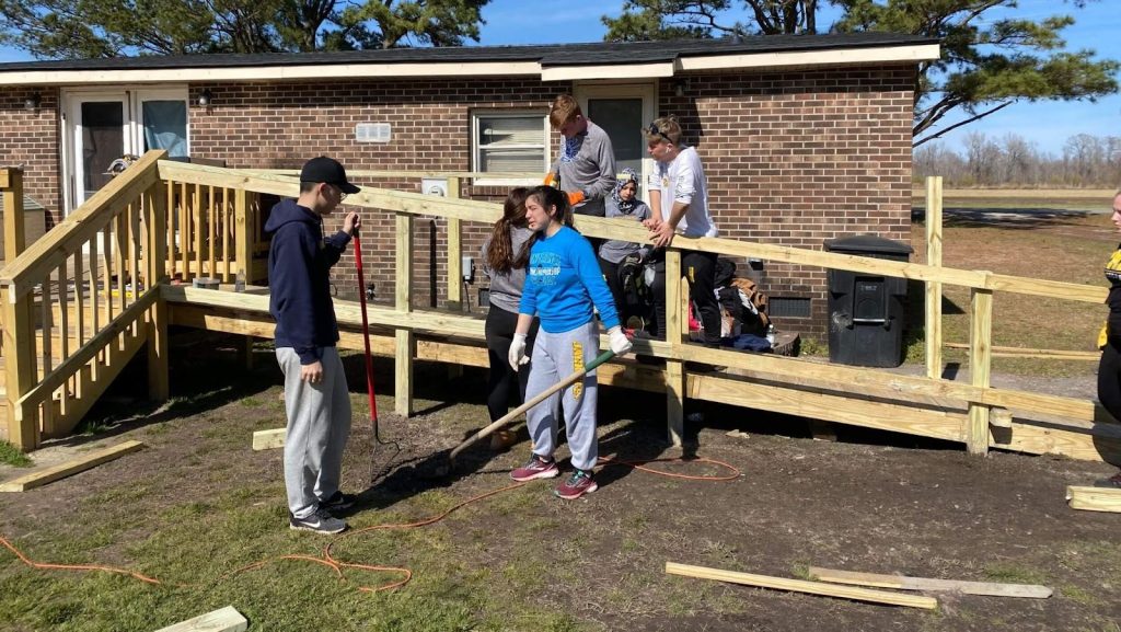 R-MA students helping an elderly couple fix their fence during a student-organized community service drive