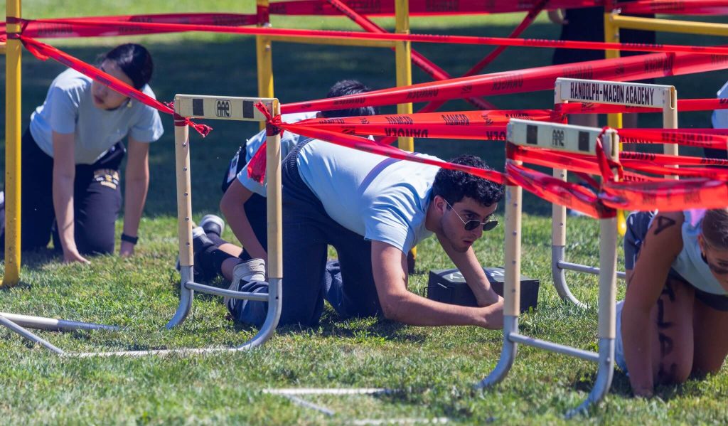 A trio of cadets navigating a leadership obstacle course as part of summer military programs at R-MA.