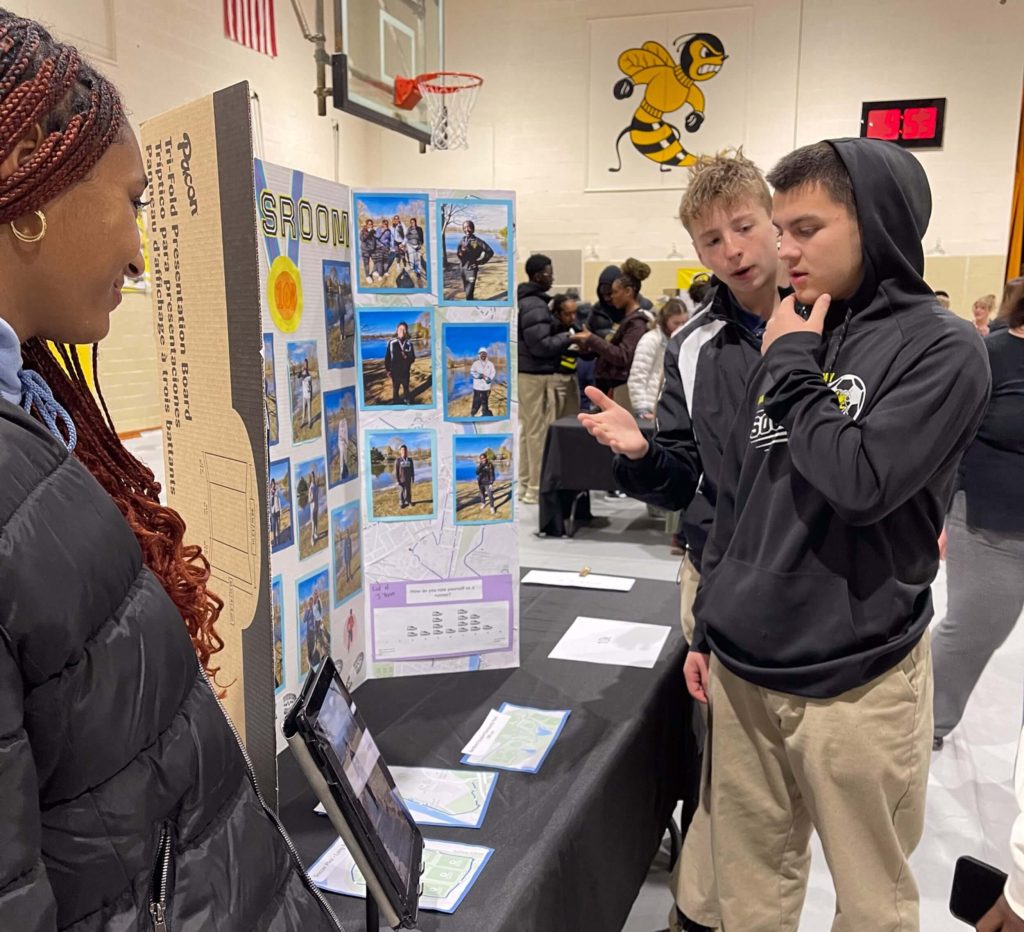 R-MA students presenting a capstone project display, highlighting experiential learning in high school and career exploration for teens