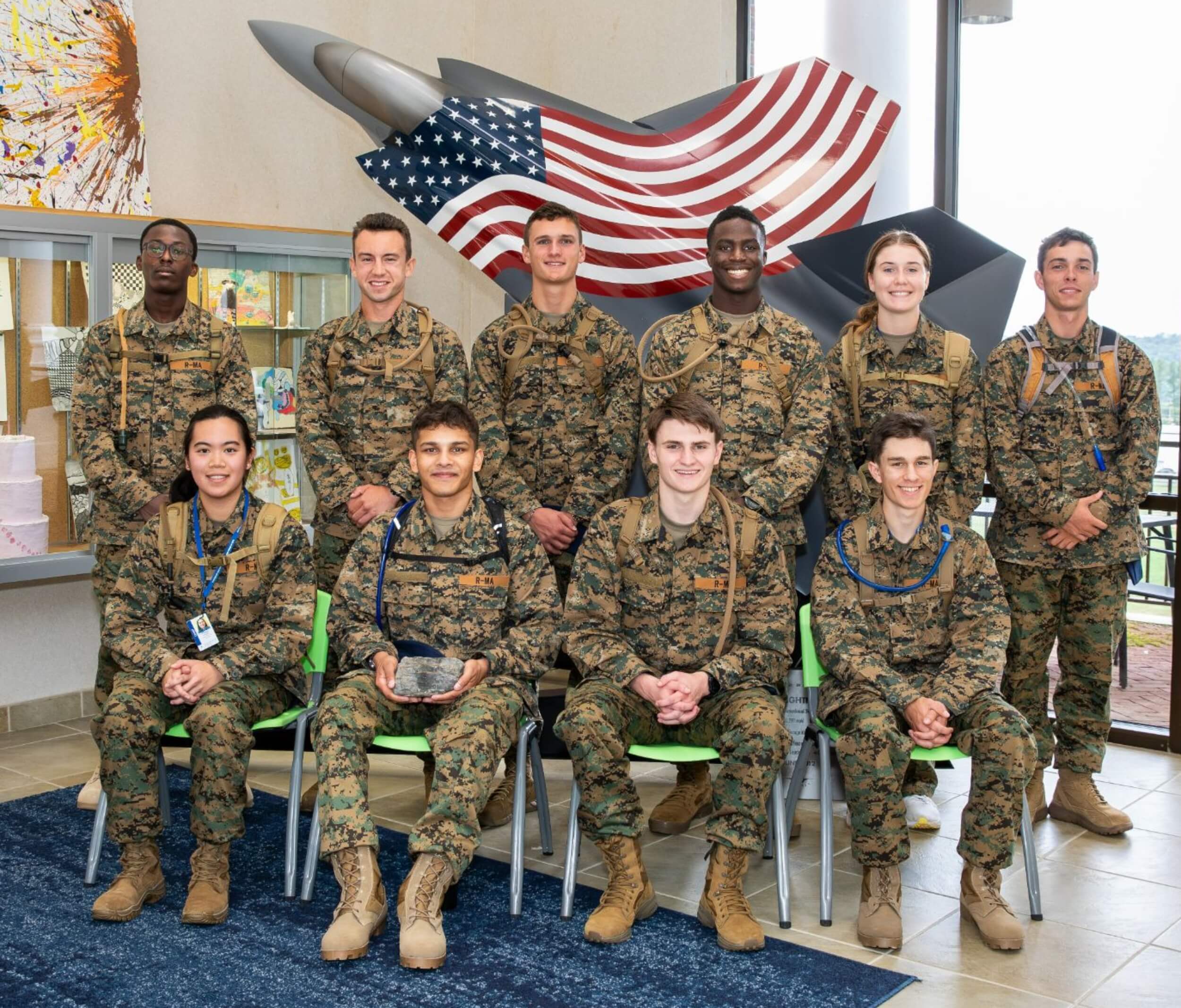 Students in Randolph-Macon Academy's aviation program for high school students pose in uniform beneath an aerospace display during a leadership and STEM learning experience.