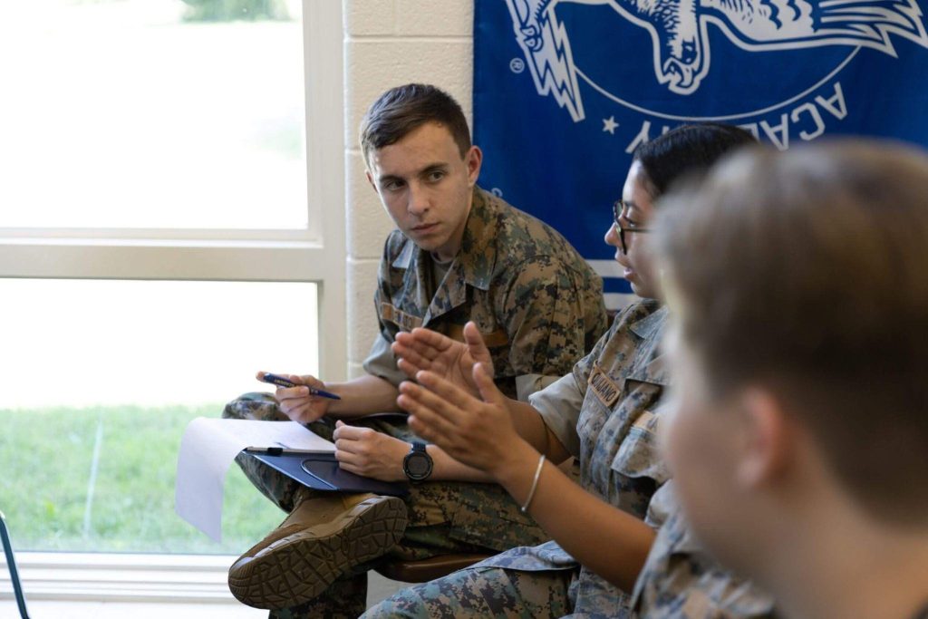 A class of R-MA cadets participating in a group discussion, showing mentorship in school and academic support for high school students