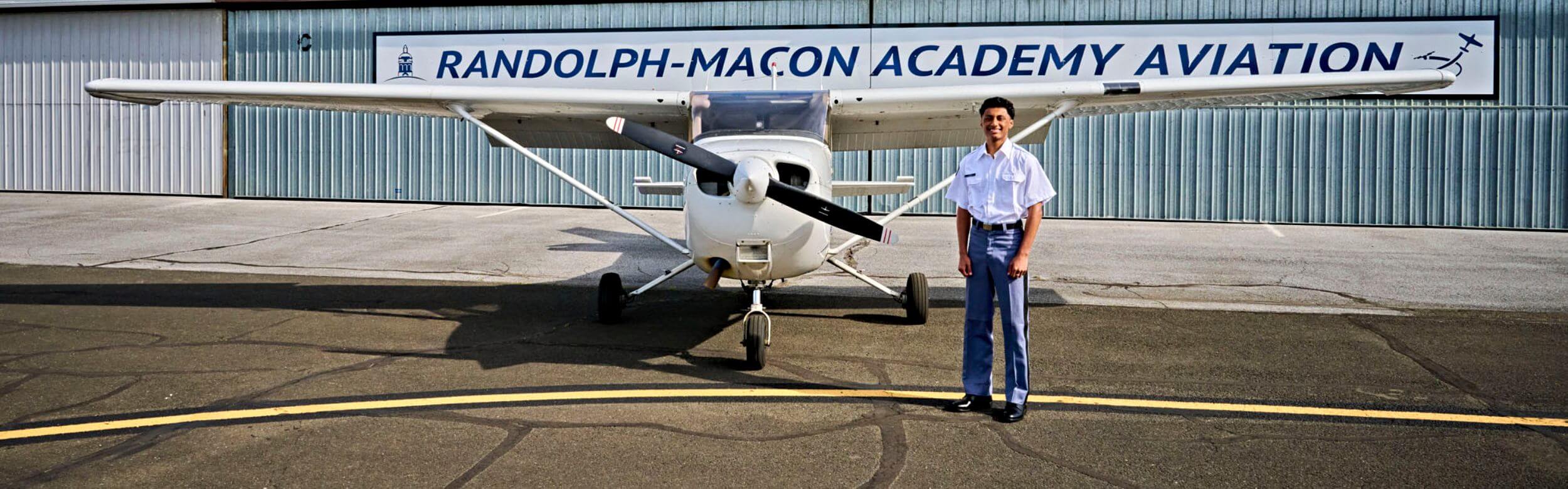 A Randolph-Macon Academy student stands beside a training aircraft as part of a high school aviation program that builds STEM skills, confidence, and college readiness.