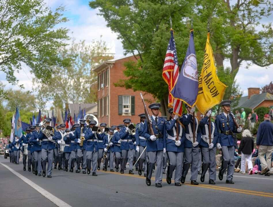 Randolph-Macon Academy cadets marching with the school band and color guard, showing community involvement and student life at boarding school.