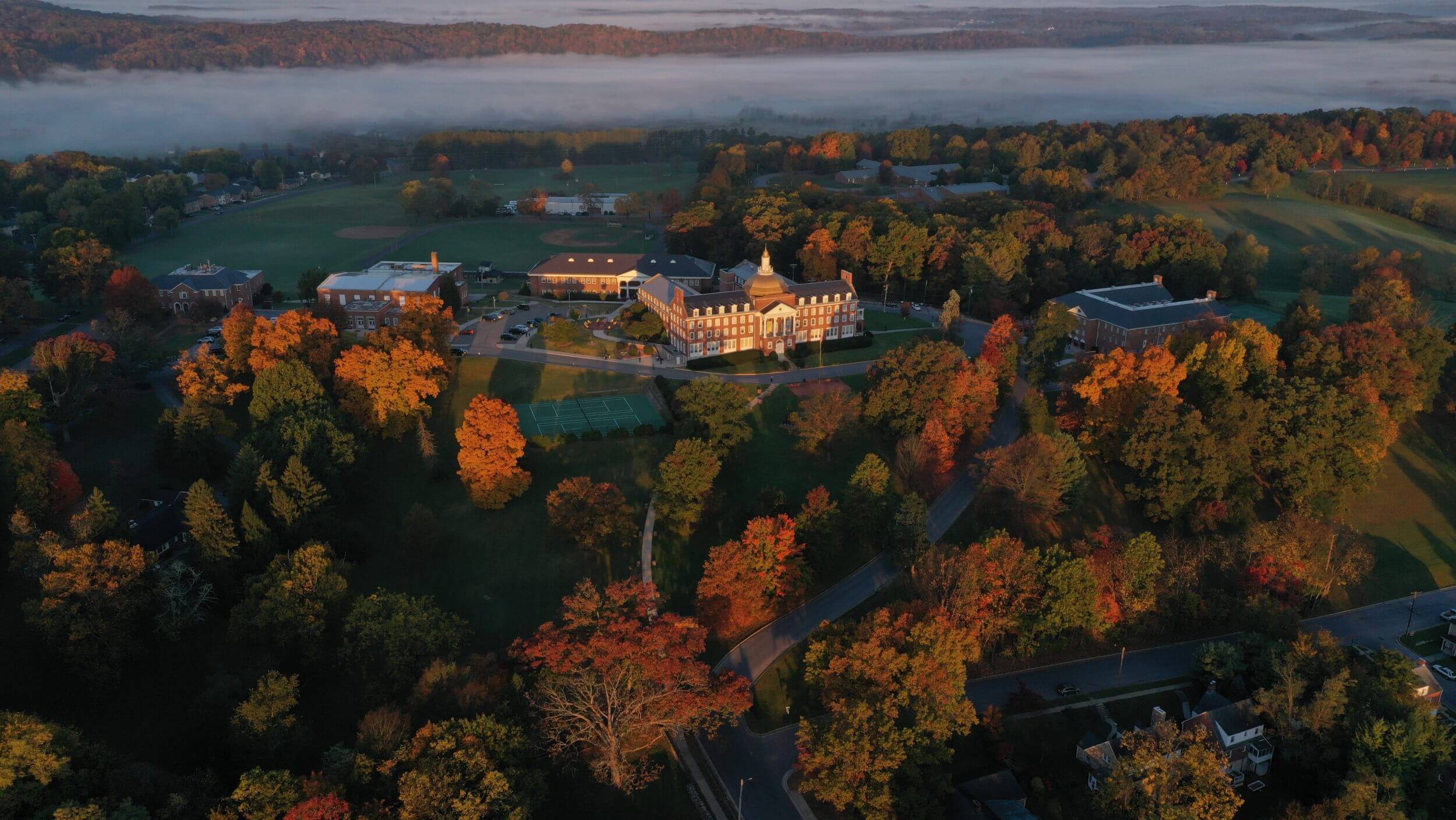 Aerial view of the Randolph-Macon Academy boarding school campus during fall, showing academic buildings, athletic fields, and the surrounding community.