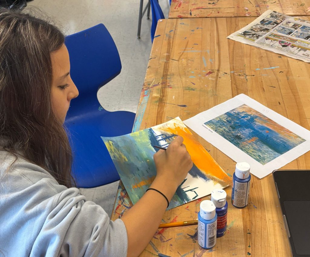 An R-MA student painting with watercolours, representing extracurricular activities for high school students
