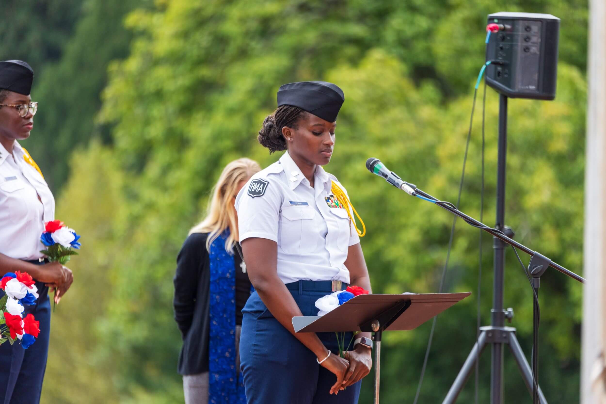A female R-MA cadet speaking at an outdoor ceremony, demonstrating confidence and military school leadership for girls.