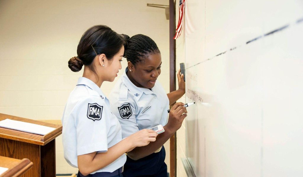 Two R-MA cadets collaborating on an academic problem at a classroom whiteboard.