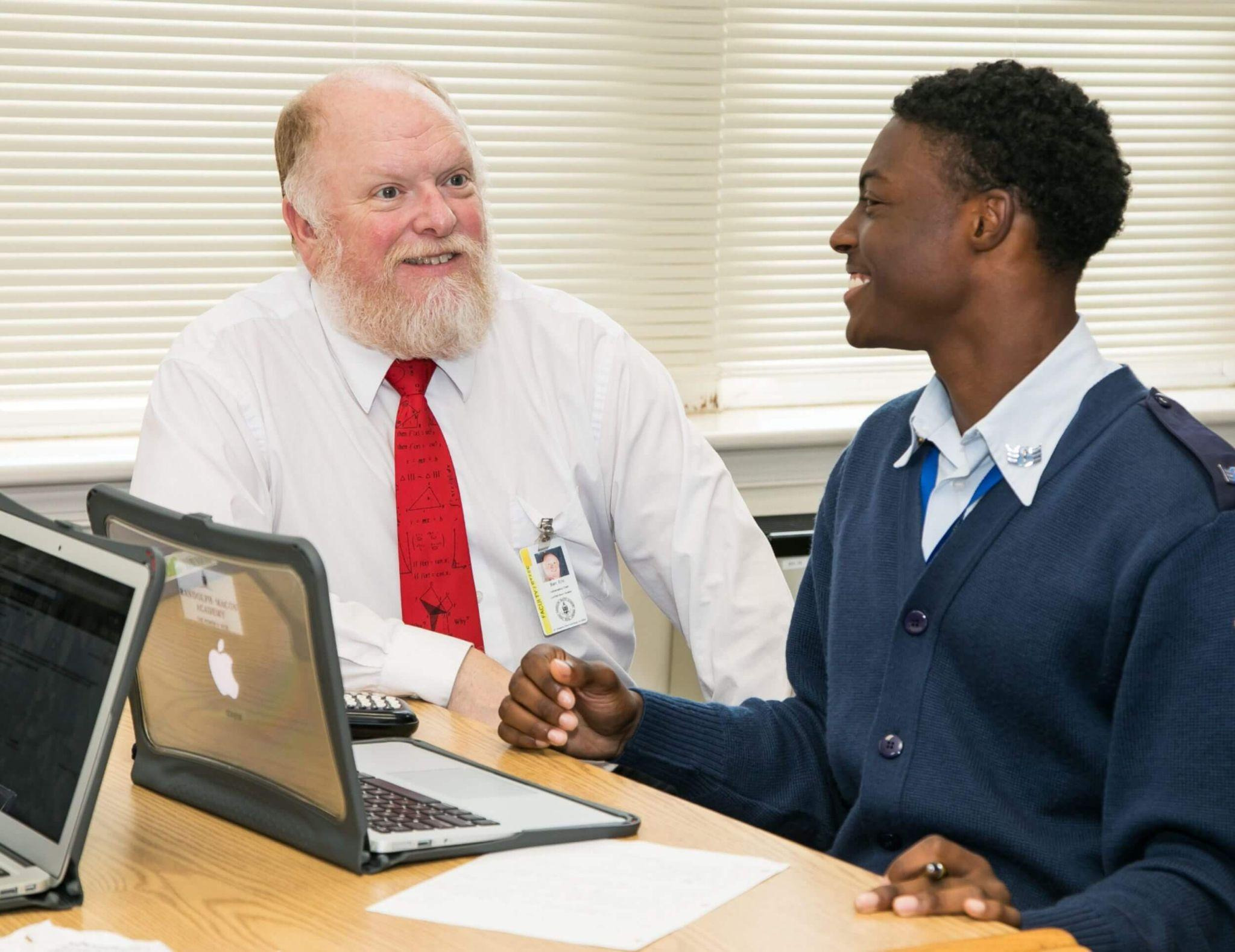 An R-MA student discussing academic work with a teacher during a classroom learning session.